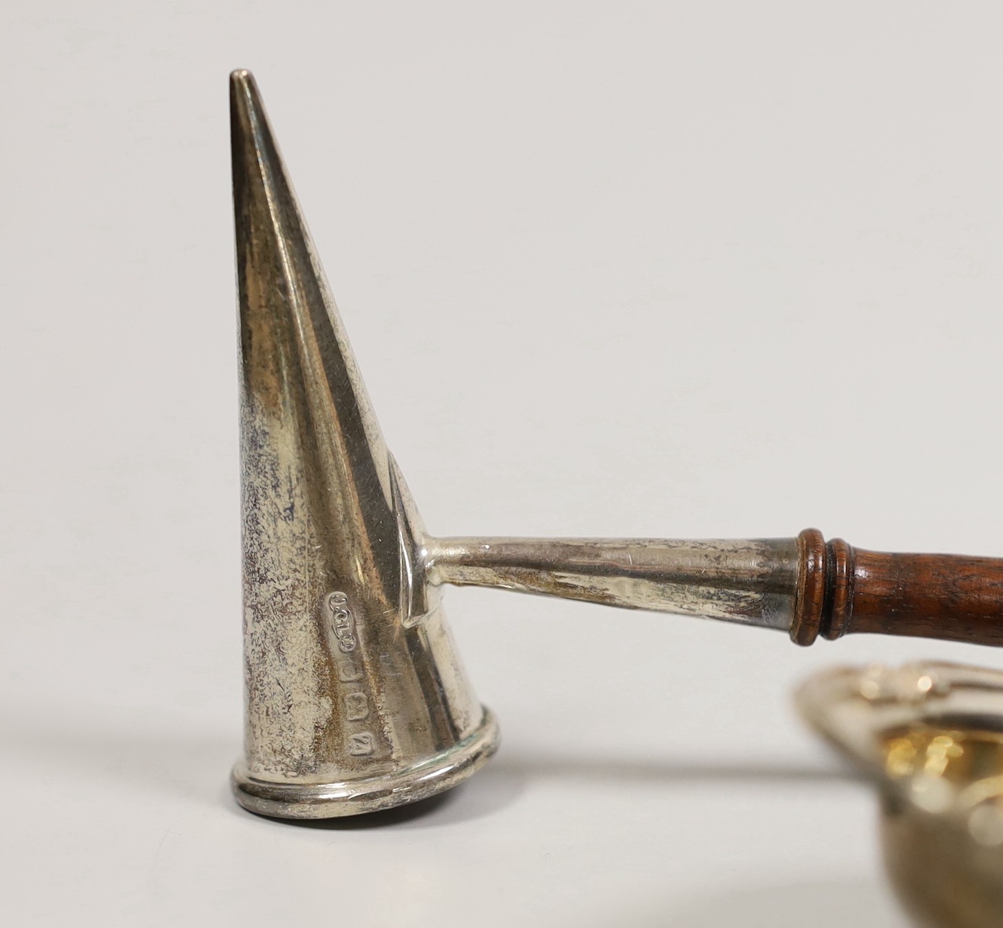 A George V silver extinguisher, with turned wooden handle, 30.8cm, a silver tea strainer, a silver and enamel ashtray and a wooden gavel.